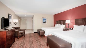 A hotel room with two beds, a TV, a desk, and a chair.