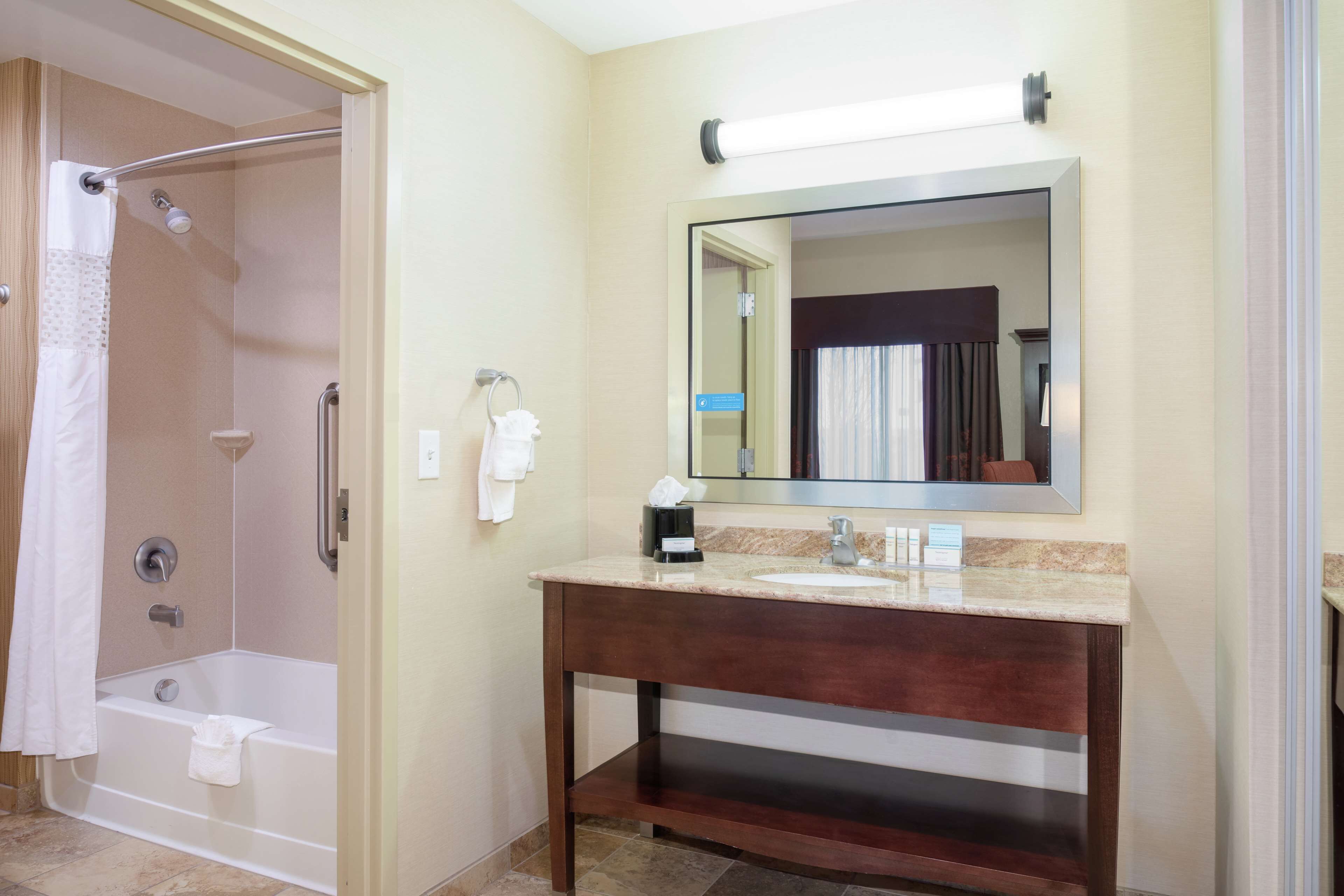 Une salle de bain équipée d’une douche, d’un lavabo, d’un miroir et d’un porte-serviettes.