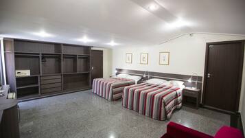 A bedroom with two beds, a wardrobe, a desk, and a red chair.