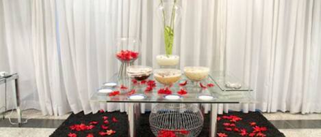 A glass table with vases and bowls, surrounded by a black rug with red flowers.