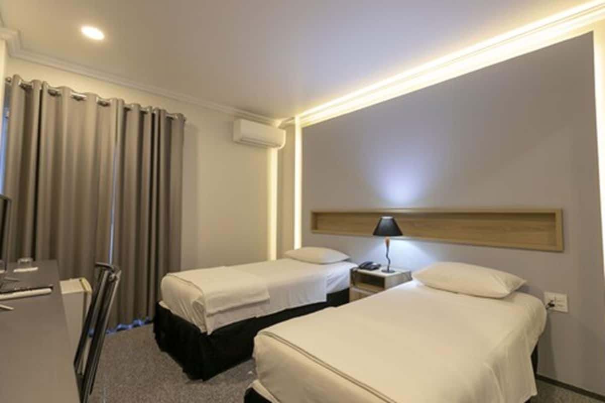A hotel room with two beds, a desk, and a chair.