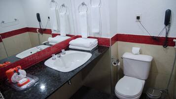 Un baño con lavamanos, inodoro y dos secadores de manos.