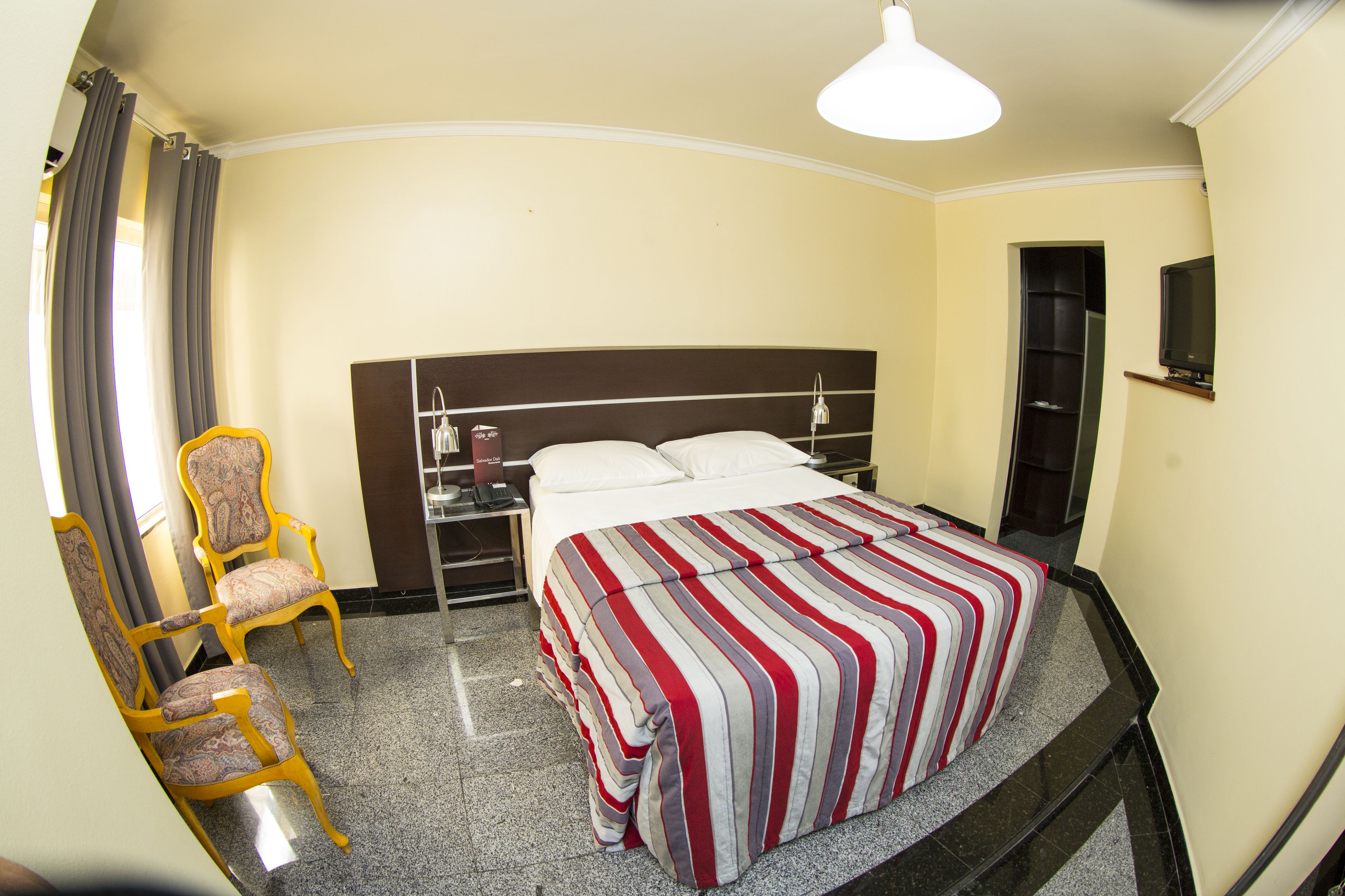 Una habitación de hotel con una cama, una silla, un escritorio y una televisión.