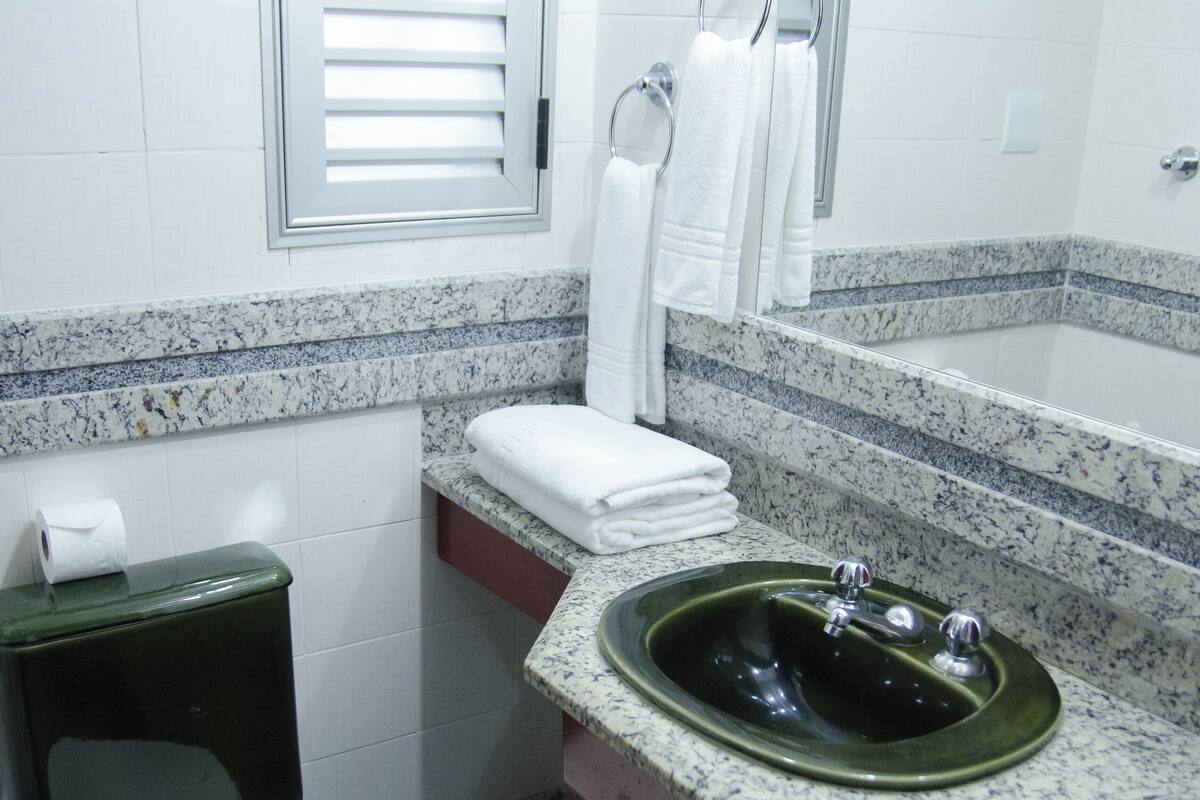 A bathroom with a toilet, sink, and towel rack.