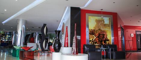 Un vestíbulo moderno con mostrador de recepción, zona de estar y jarrones decorativos.