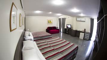 Una habitación de hotel con dos camas, un escritorio, un televisor y una kitchenette.