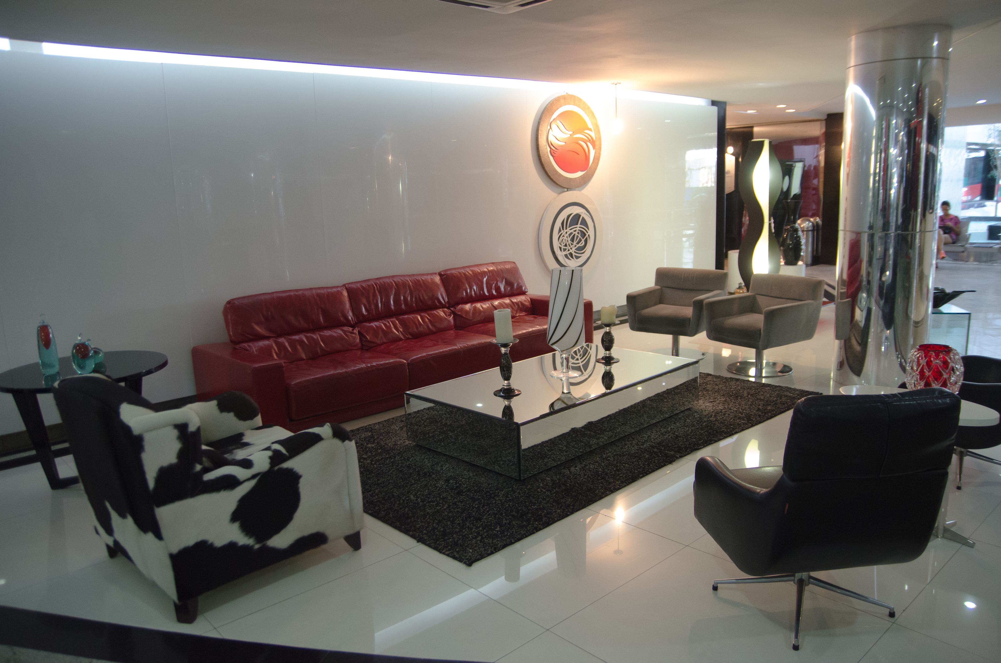 A modern living room with a red sofa, black and white armchair, and a glass coffee table.