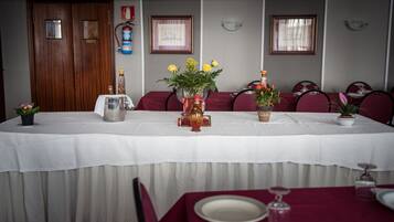 Una mesa de comedor con manteles blancos, sillas rojas y centros de mesa florales.