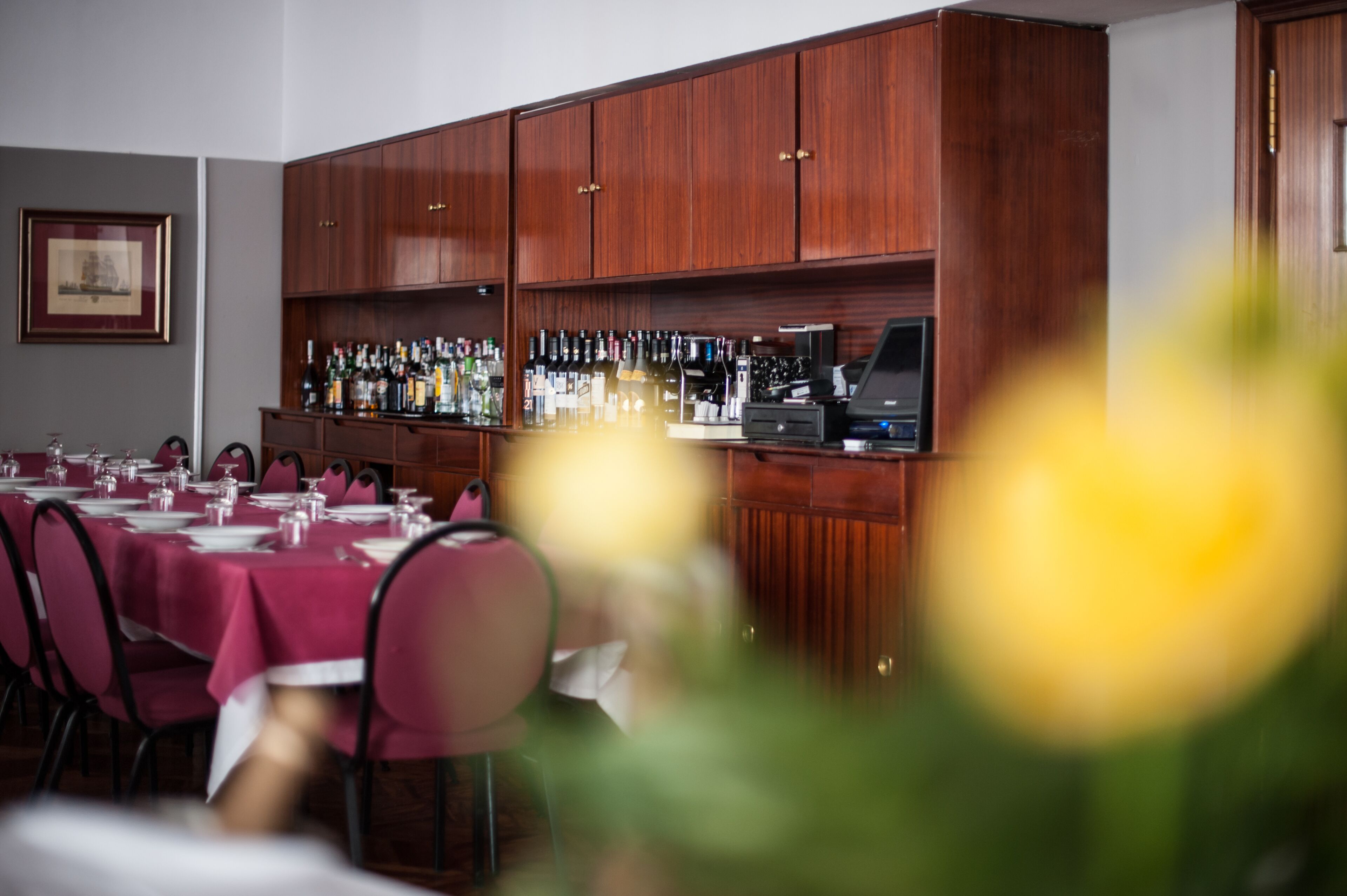 Un restaurante con barra, armarios de madera y una larga mesa dispuesta para comer.