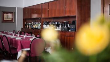 Un restaurante con barra, armarios de madera y una larga mesa dispuesta para comer.