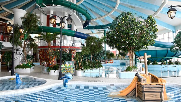 An indoor water park with a pool, slides, and a tiki bar. - Pite Havsbad (Pitea)