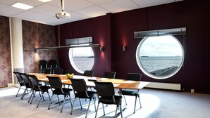 A conference room with a large table, chairs, and two large windows offering a view of the sea. - Pite Havsbad (Pitea)