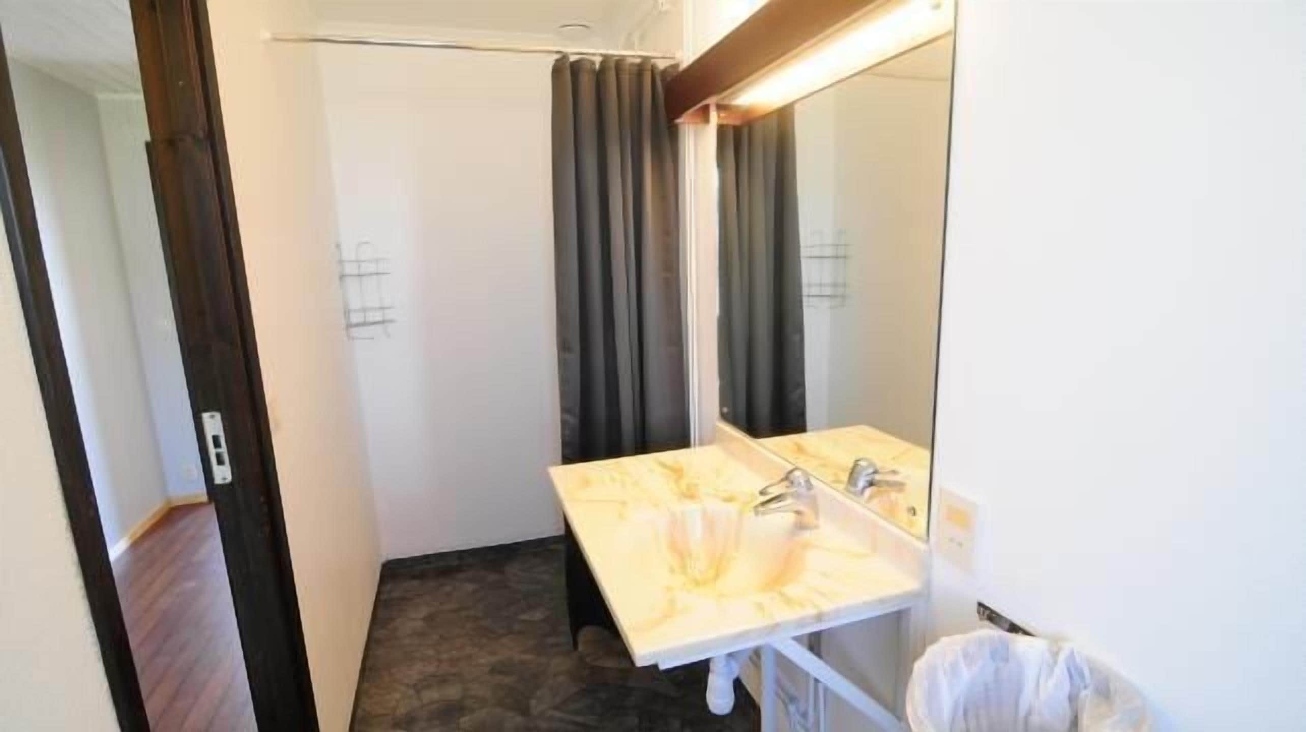 A bathroom with a marble sink, a mirror, and a shower curtain.