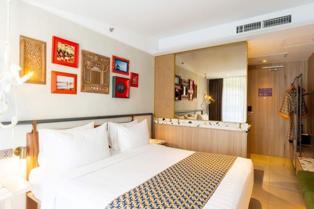 Une chambre d’hôtel avec un grand lit, un miroir et une armoire.