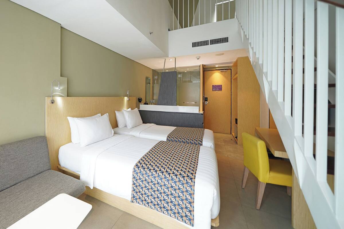 Une chambre d’hôtel moderne avec un grand lit, un bureau et un escalier.