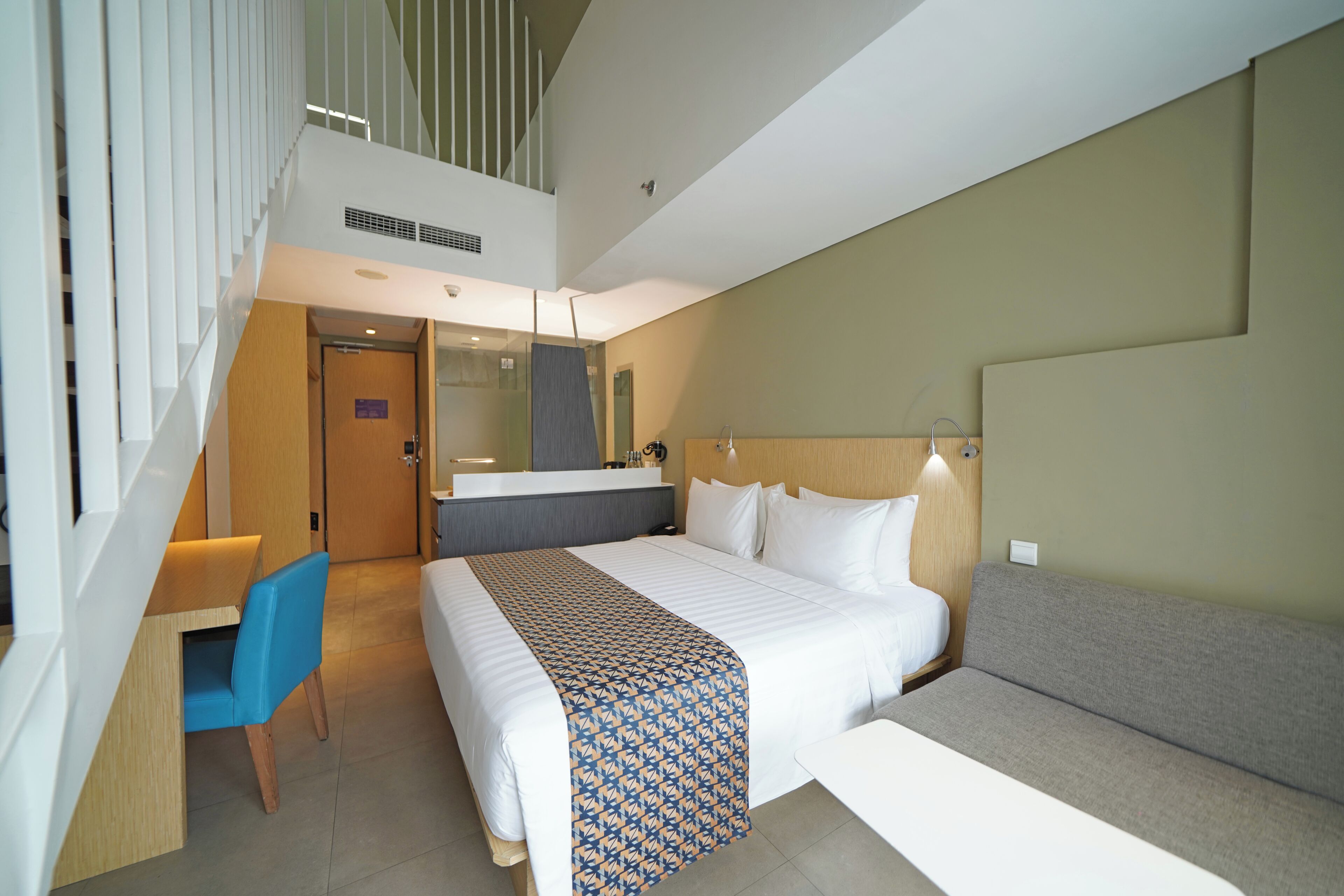 Una habitación de hotel con cama, sofá, escritorio y una silla.