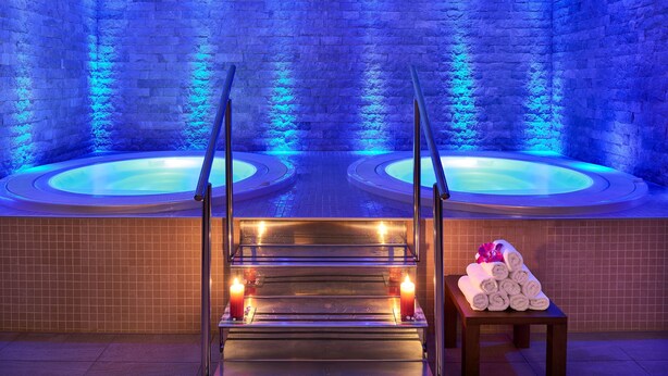 A spa area with two hot tubs, a wooden bench, and candles. - Medjugorje Hotel & Spa (Citluk)