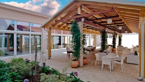 An outdoor patio with wooden beams, white furniture, and potted plants. - Medjugorje Hotel & Spa (Citluk)
