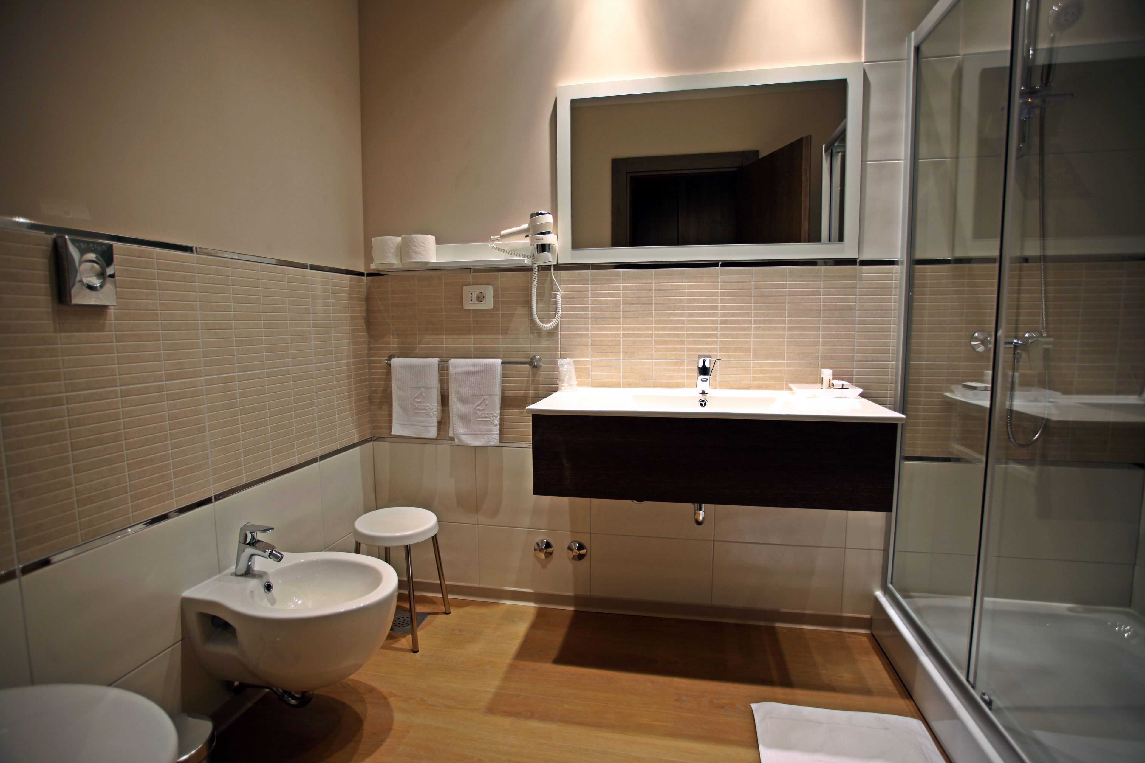 A modern bathroom with a sink, bidet, and glass-enclosed shower.