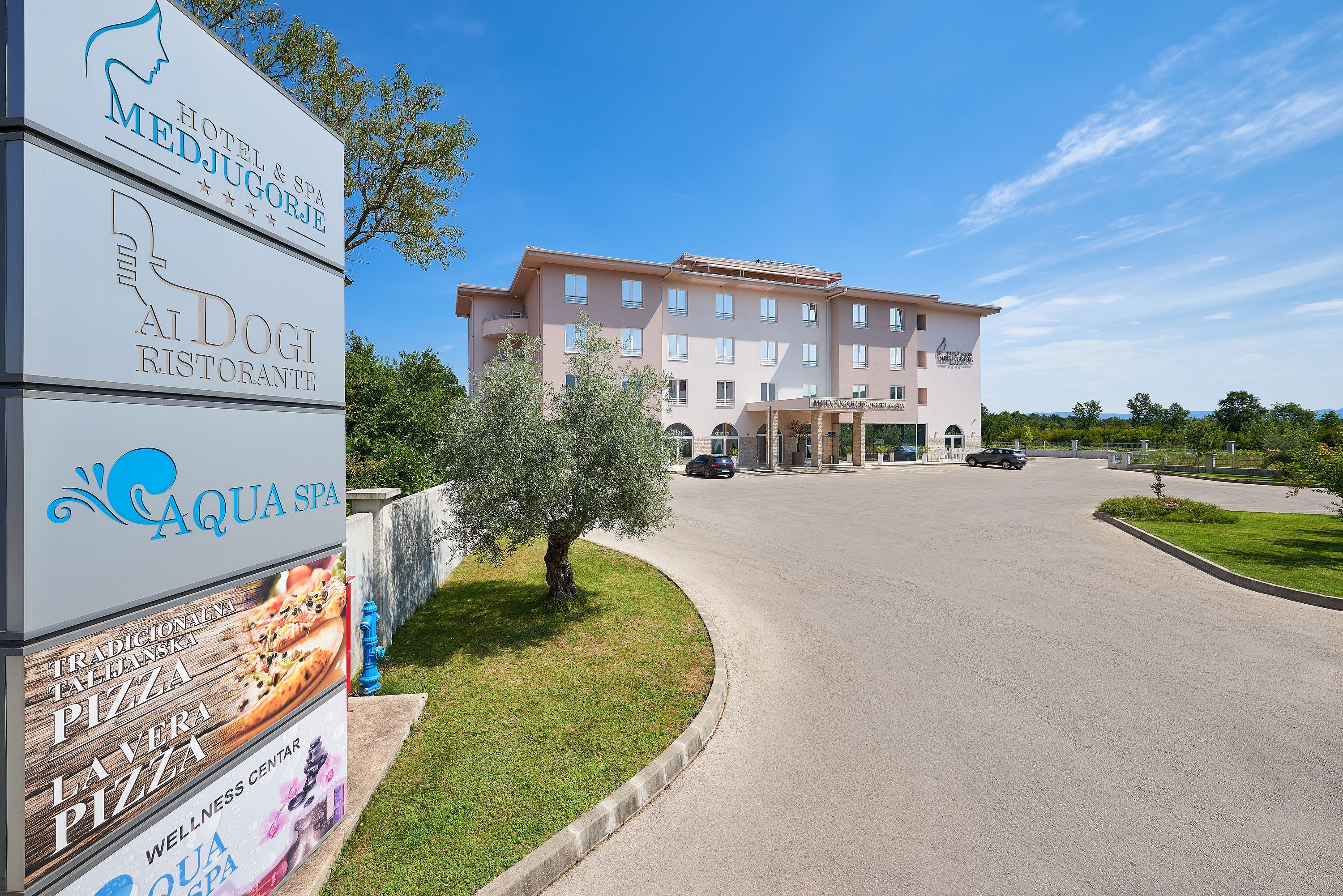 A hotel with a signboard advertising a restaurant, spa, and wellness center.