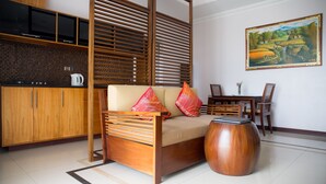 A modern living room with a sofa, wooden side table, and a painting on the wall. - Jimbaran Cliffs Private Pool Hotel & Spa (Nusa Dua)