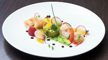 A white plate with a seafood dish, including shrimp and avocado, on a dark wooden table.