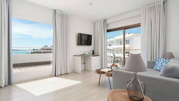 Een moderne hotelkamer met balkon, een flatscreen televisie, een bank, een bijzettafeltje en een bureau.