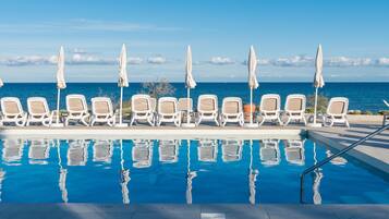 Een buitenzwembad, ligstoelen bij het zwembad