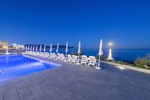 Una piscina al aire libre, sillones reclinables de piscina