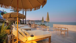 Zona relax a la platja amb gandules, una taula i cadires, amb vista al mar.