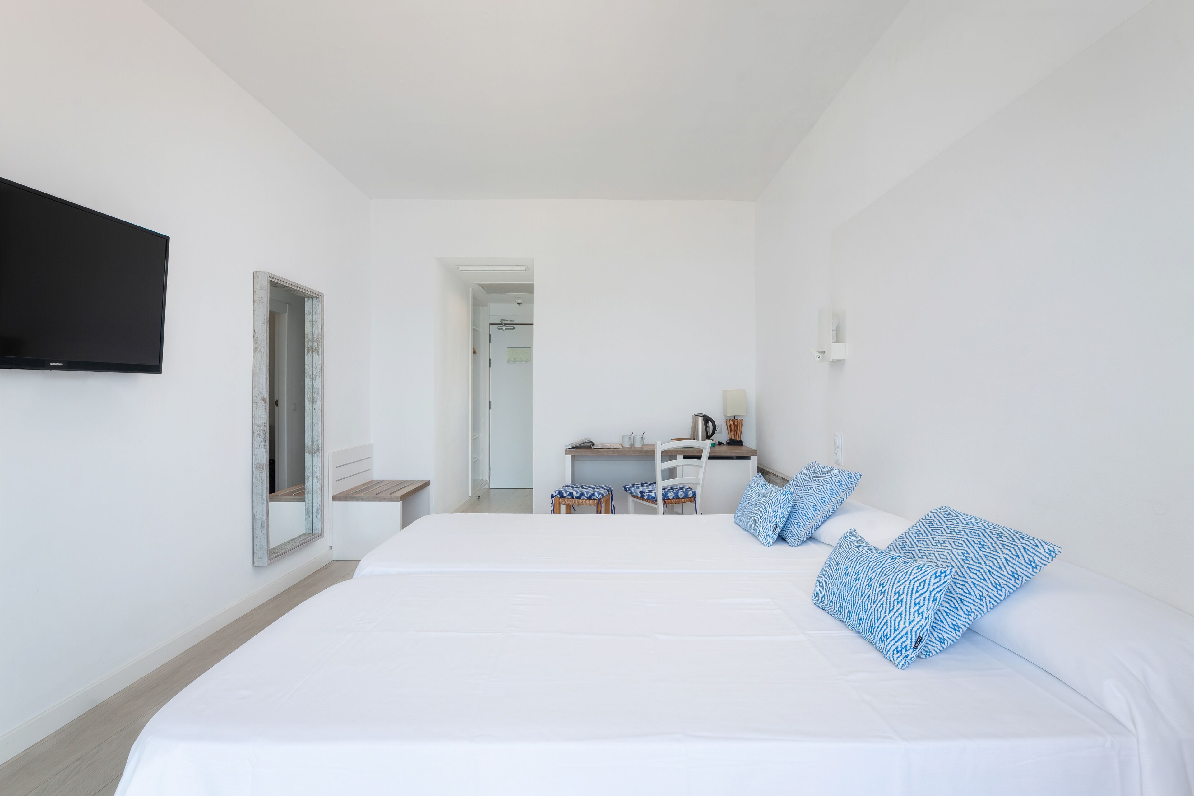 A hotel room with a large bed, a desk, and a television.