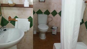 Un baño con lavamanos, inodoro y cortina de ducha.