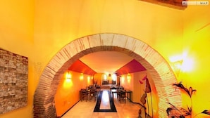 A restaurant with a stone archway, wooden tables, and chairs, and a central bar area.