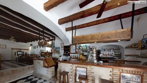 A bar area with wooden stools, a checkered floor, and exposed wooden beams.