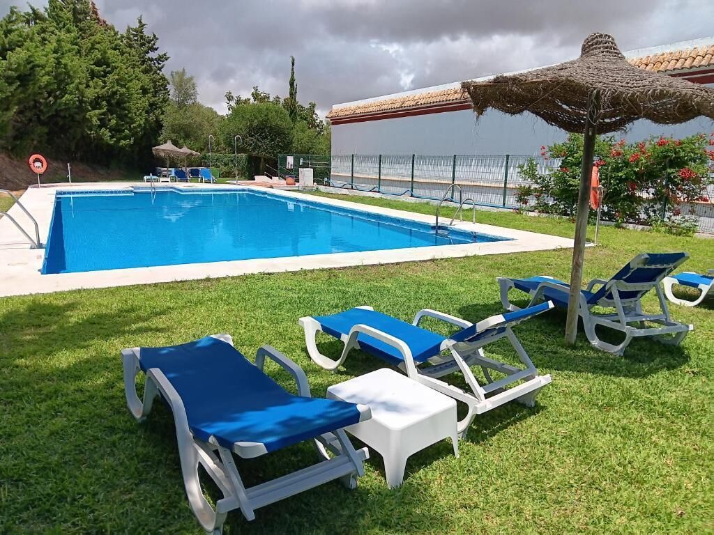 Una piscina al aire libre, sombrillas, sillones reclinables de piscina