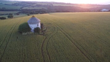Eine Luftaufnahme einer ländlichen Landschaft mit einem einzelnen, turmartigen Bau inmitten von Feldern.