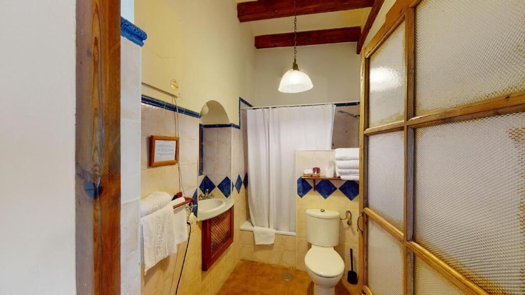 A bathroom with a shower, toilet, sink, and a towel rack.