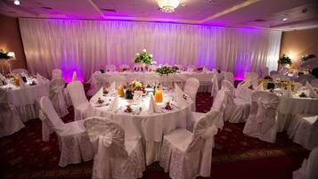 A banquet hall with round tables, white tablecloths, and chairs with white sashes.