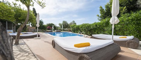 Una piscina al aire libre, sombrillas, sillones reclinables de piscina