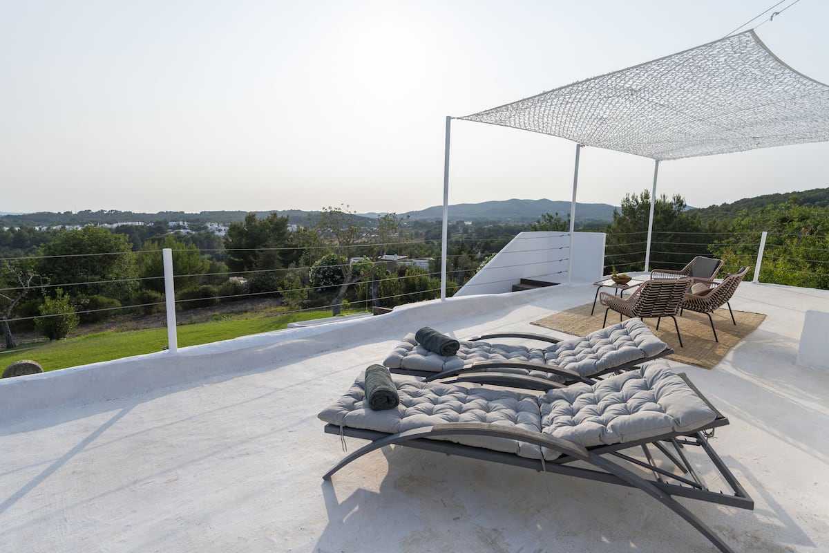 Una terrazza sul tetto con poltrone e un tavolo, che offre una vista del paesaggio circostante.