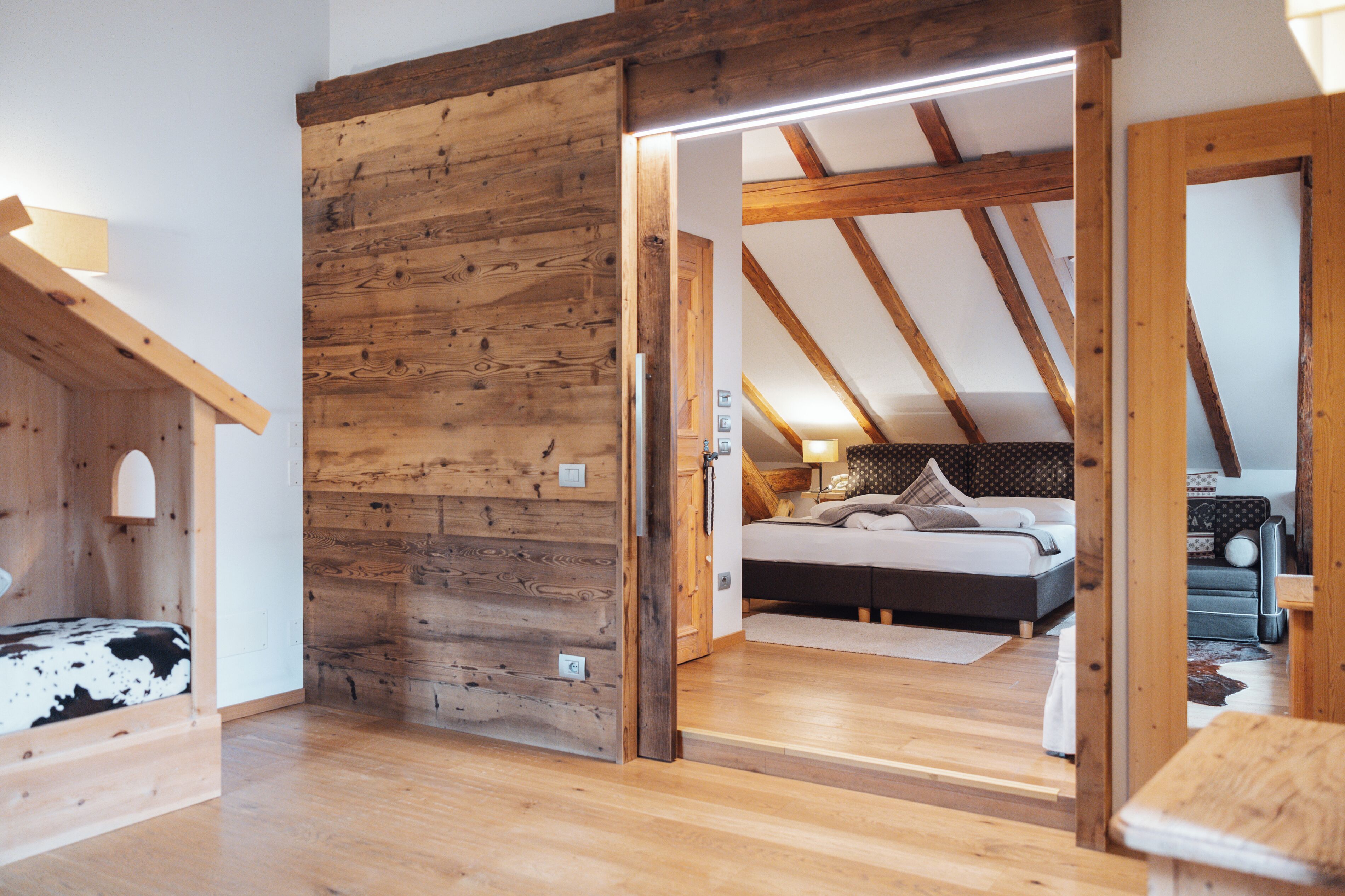 A wooden interior with a bed, a sofa, and a wooden bench.