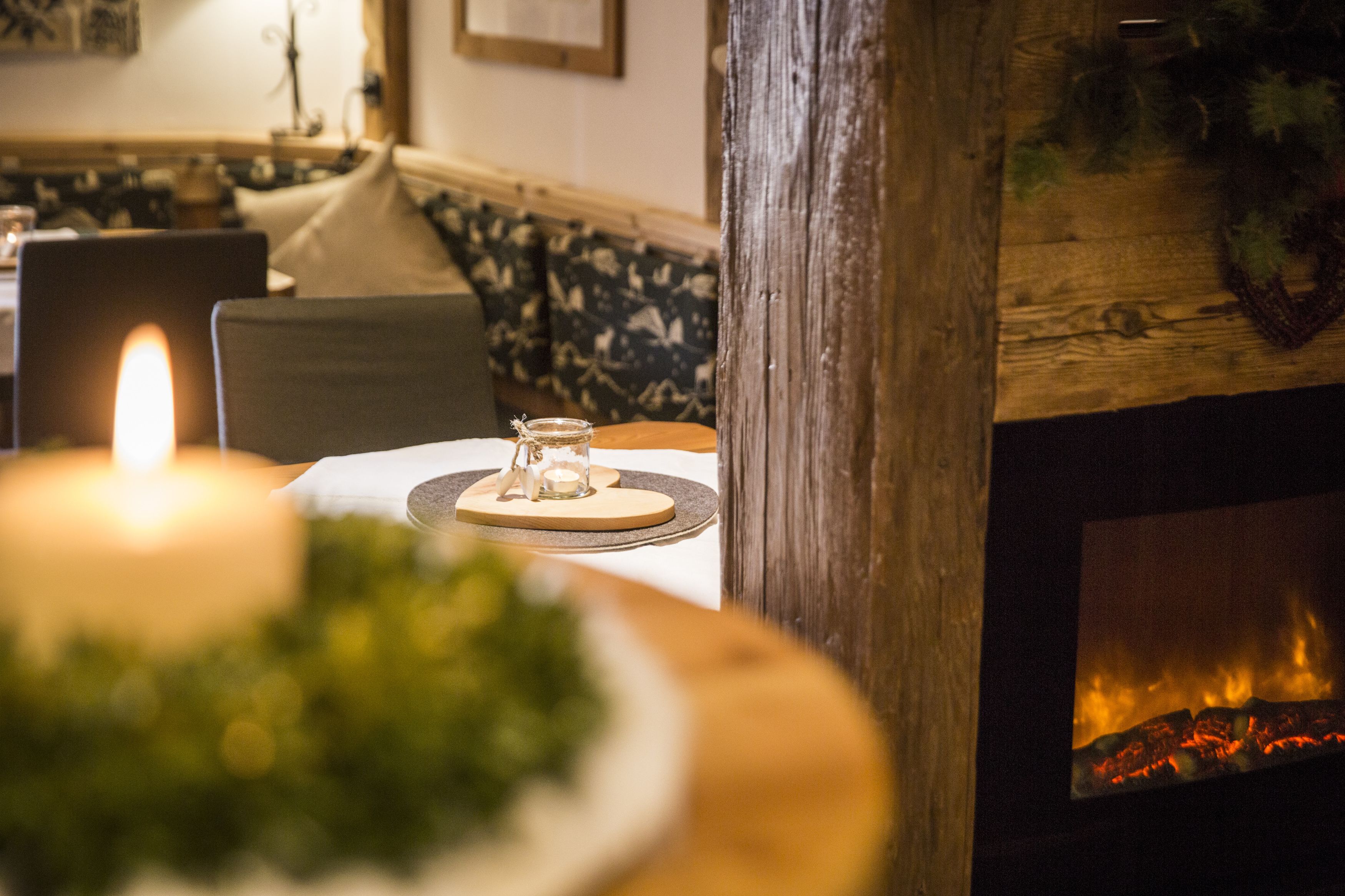 A cozy dining area with a lit candle, a wooden table, and a fireplace.