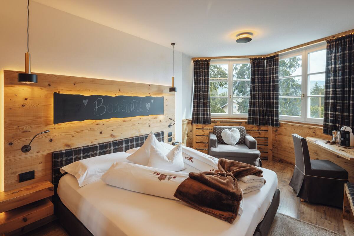 A cozy room with a bed, a desk, and a window with curtains.