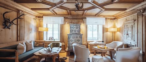 A cozy room with wooden walls, a sofa, chairs, a table, and a patterned rug.