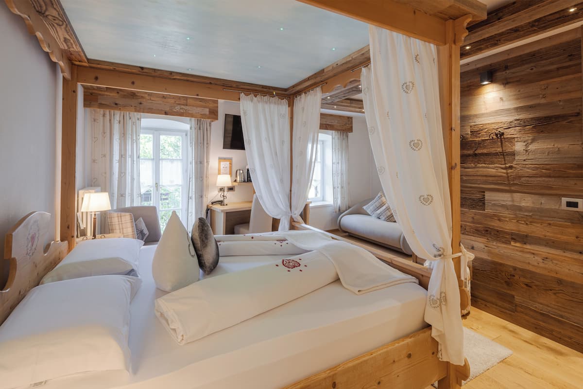 A wooden cabin bedroom with a bed, a nightstand, a lamp, and a window with curtains.