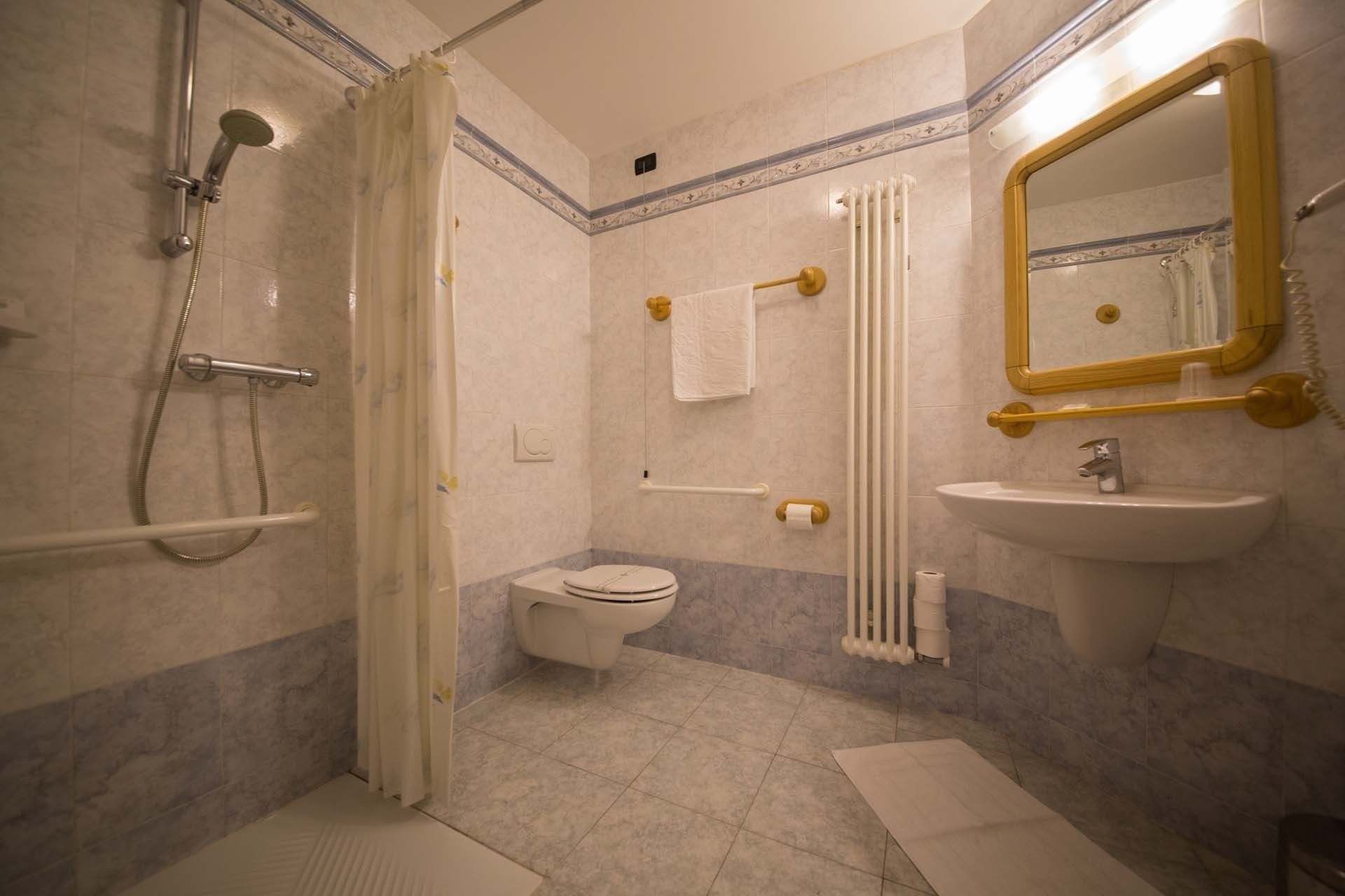 A bathroom with a shower, toilet, sink, and mirror.