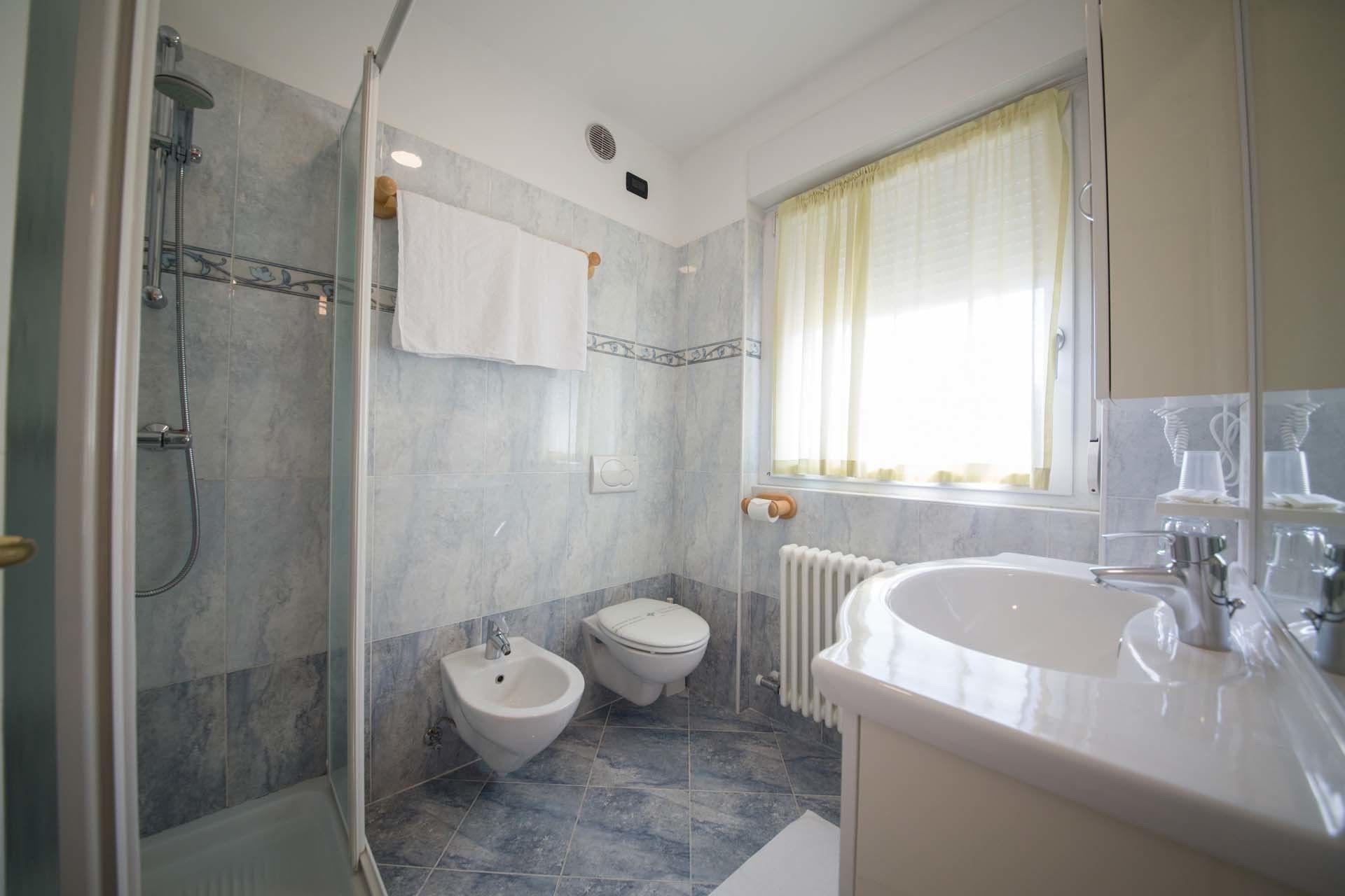 Egy fürdőszoba zuhanyzóval, bidével, WC-vel és mosdókagylóval.