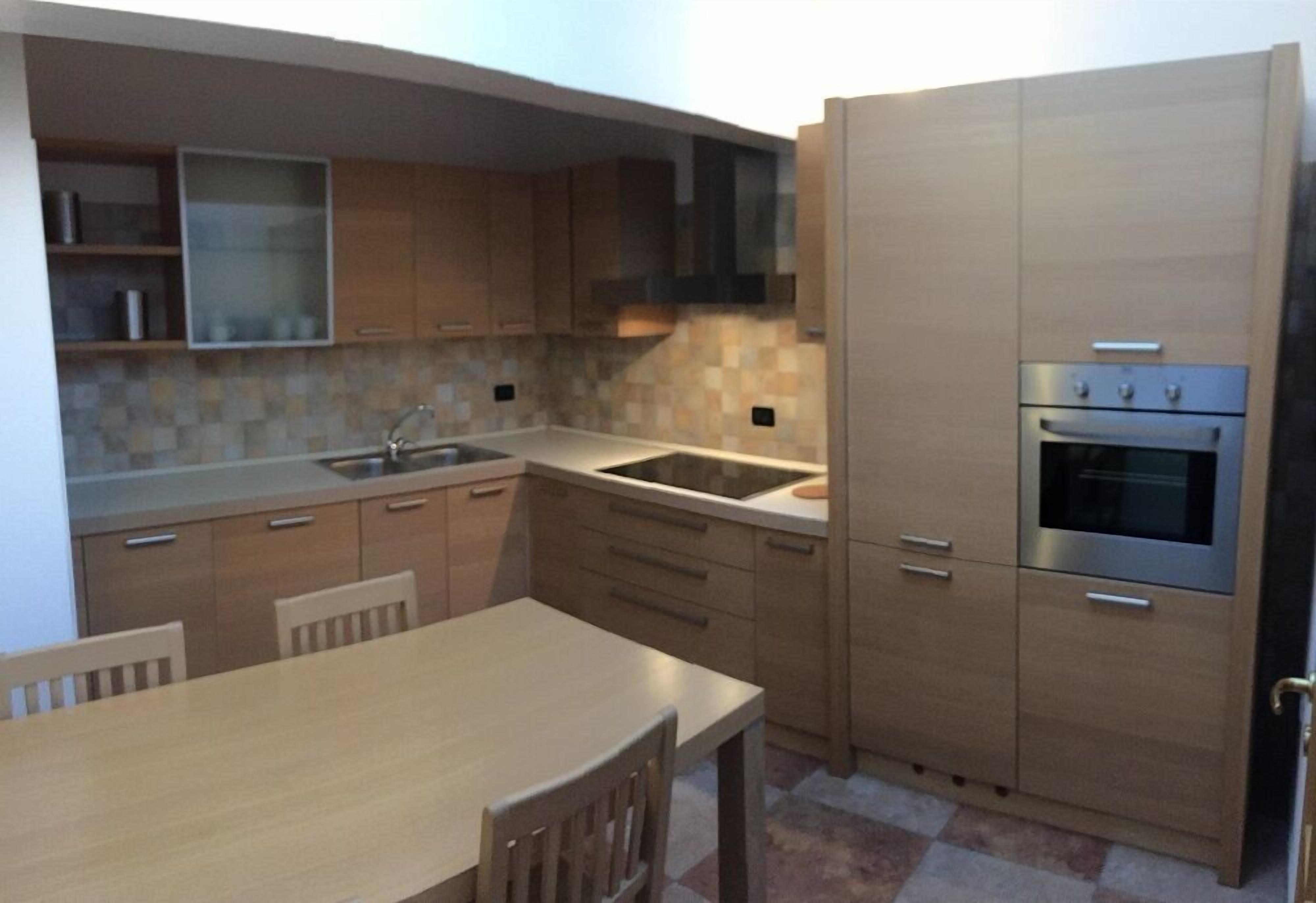 A modern kitchen with wooden cabinets, a stainless steel sink, and a built-in oven.