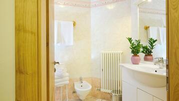 Un baño con un bidé, un lavabo, dos plantas en macetas y un perchero para toallas.