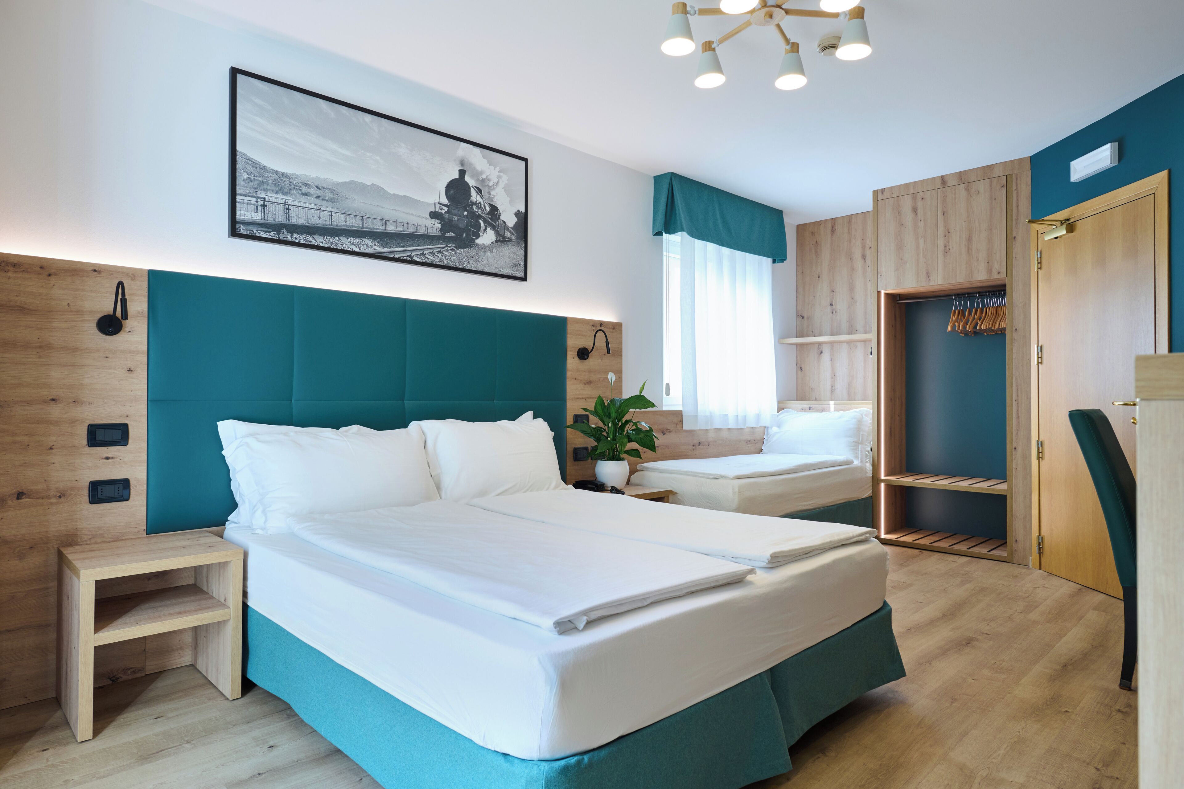 Habitación de hotel moderna con una cama grande, una mesita de noche, un armario y un cuadro en la pared.